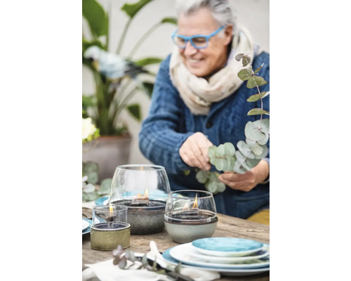 Lămpi decorative cu ulei pe o masă afară cu o persoană în fundal