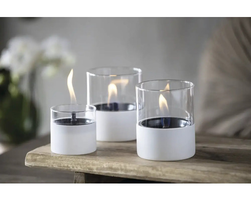 Trei focuri de masă cu cilindru de sticlă și bază albă pe o masă de lemn