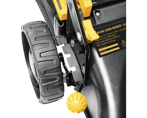 Prim-plan cu o mașină de tuns iarba, cu accent pe roată, reglarea înălțimii și eticheta cu datele tehnice.