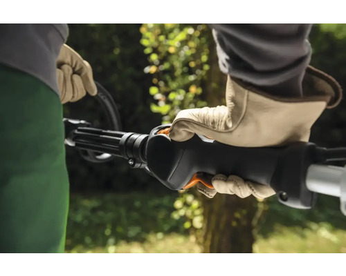 O persoană operează o motocoasă purtând mănuși.