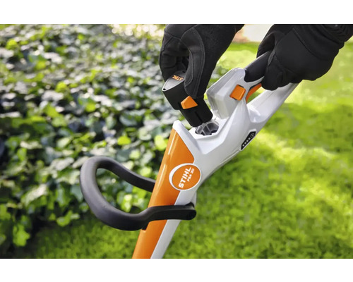 O persoană introduce o baterie într-o mașină de tuns iarba fără fir.