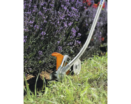 Motocoasă la lucru în grădină lângă lavandă