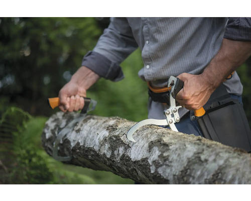 Bărbat taie un trunchi de copac cu un lanț de tăiat crengi și un țapinar