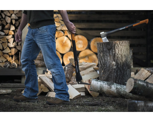Bărbat cu topor de despicat în fața unui stoc de lemn