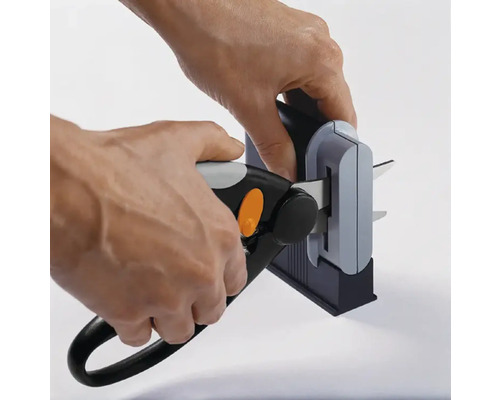 O persoană ascuțește o foarfecă de grădină cu o ascuțitoare.