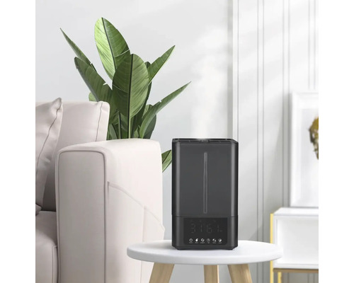 Umidificator pe o masă lângă o canapea și o plantă