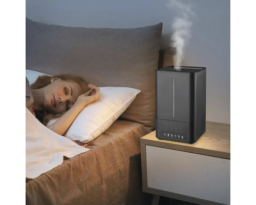 Umidificator pe o noptieră lângă o persoană care doarme