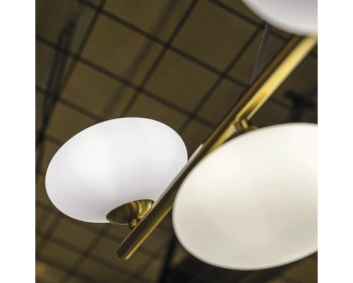 Prim-plan cu o lustră cu mai multe abajururi rotunde albe pe tije aurii.