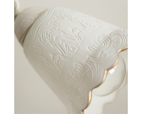 Prim-plan al unei lămpi de tavan albe cu model floral și margine aurie