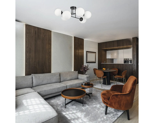 Living luminos cu canapea de colț gri, măsuțe de cafea, zonă de luat masa și lampă de tavan cu mai multe abajururi.