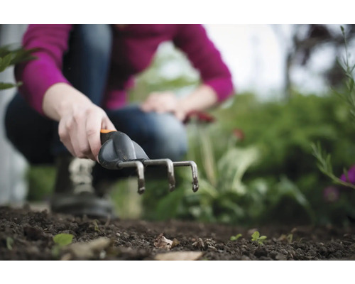 O persoană folosește un cultivator în grădină.