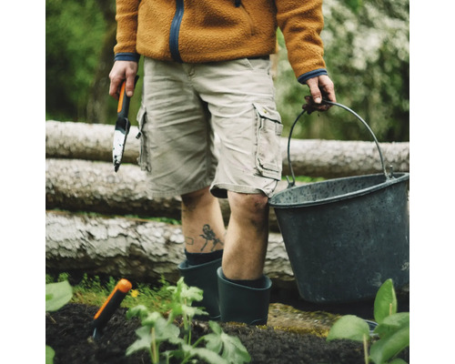 Persoană cu lopată de grădină, găleată și unelte de grădinărit în timpul grădinăritului