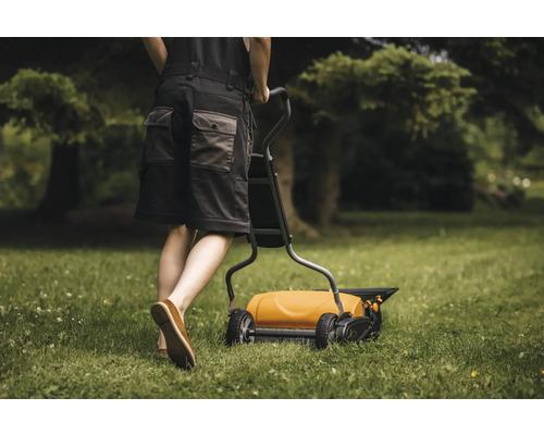 O persoană folosește un aerator de gazon în grădină.