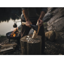 Bărbat taie lemne cu un topor pentru un foc de tabără