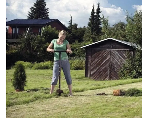 Femeie care plantează copaci în grădină cu un instrument de plantare.