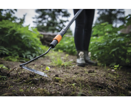 Persoană care folosește o sapă oscilantă în grădină pentru plivire.