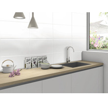 Bucătărie luminoasă cu chiuvetă, robinet, veselă și ceai de plante în fața faianței albe