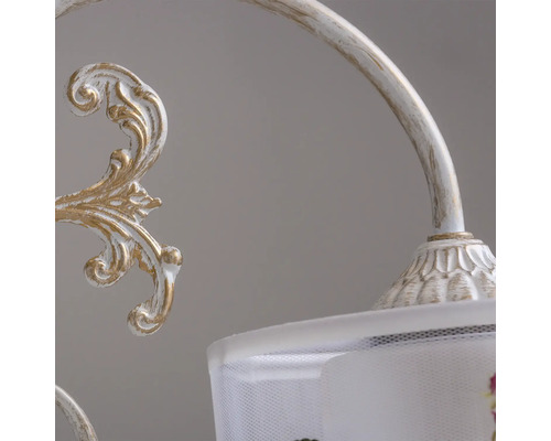 Prim-plan al unei lămpi albe și aurii cu model floral