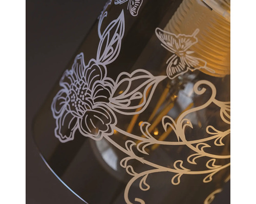 Prim-plan cu o lampă decorativă cu motive florale și un fluture