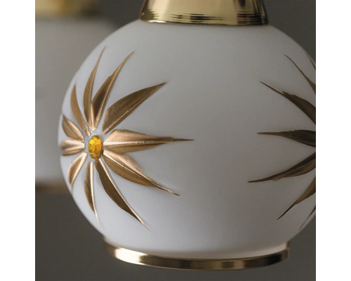 Prim-plan cu o lampă albă cu motive florale aurii