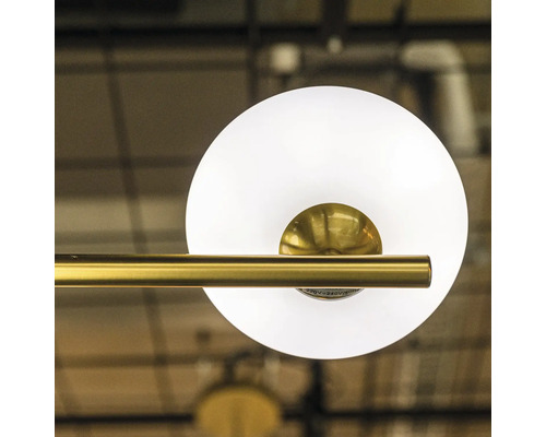 Prim-plan cu o lampă de tavan cu cadru auriu și abajur rotund din sticlă albă.