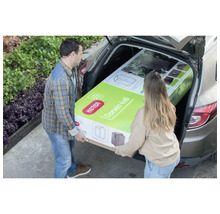 Un cuplu încarcă o magazie de grădină Keter Darwin 4x6 ambalată într-un portbagaj auto.