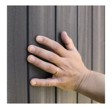 O mână atinge o placare gri a fațadei.