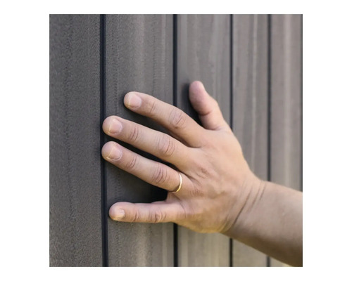 O mână atinge o placare gri a fațadei.