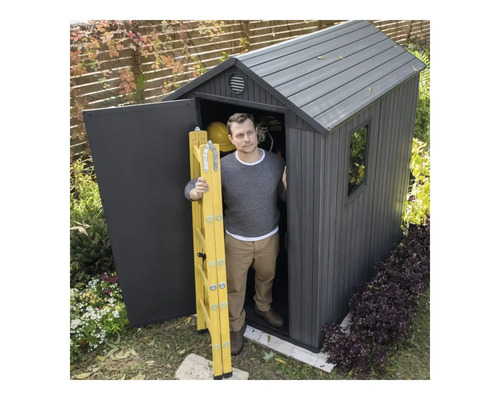 Bărbat cu scară galbenă în fața unei magazii de grădină.