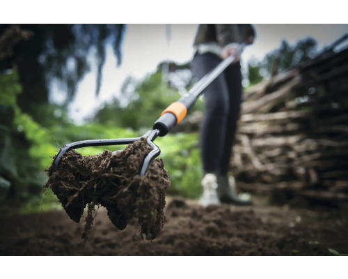 Prim-plan cu o furcă de sol cu pământ în grădină.