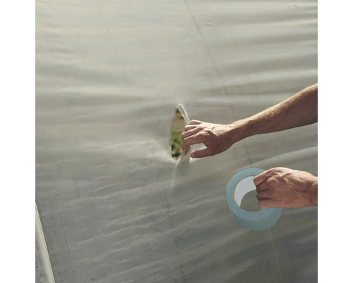 O persoană repară o gaură într-o prelată cu bandă adezivă.