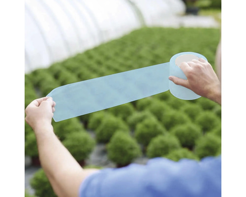 Persoană care ține folie de reparații pentru sere în fața serei