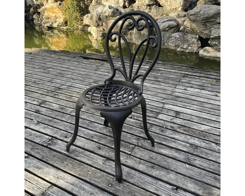 Scaun de grădină metalic cu spătar decorativ pe o terasă din lemn