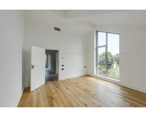 Cameră luminoasă cu podea de lemn, fereastră și ușă deschisă.