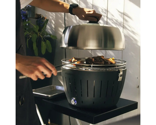 Grătar Lotusgrill cu alimente și o persoană care face grătar