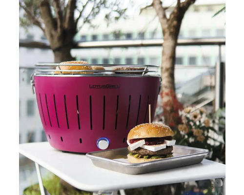 Grătar cu cărbune Lotusgrill pe o masă cu un hamburger