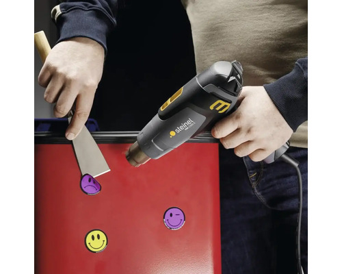 Aplicarea unui pistol cu aer cald pentru a îndepărta autocolantele de pe o suprafață cu un chit