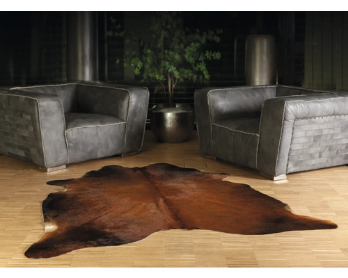 Living cu două fotolii din piele gri și un covor maro din piele de vacă