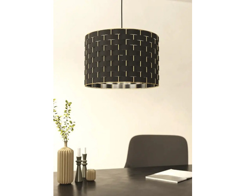 Lampa suspendată cu abajur negru și model împletit deasupra unei mese de sufragerie.