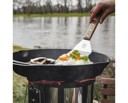 Persoană care gătește ochiuri și ciuperci într-o oală olandeză pe un aragaz