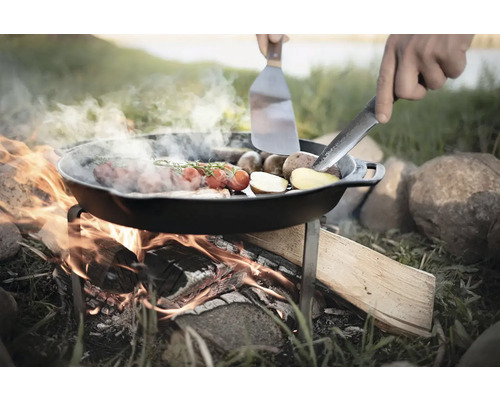 Tigaie cu alimente pe foc deschis cu ustensile de bucătărie