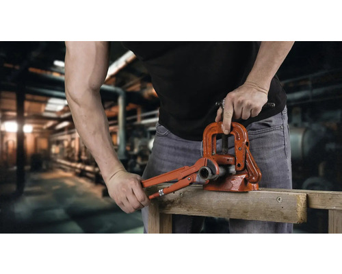 O persoană operează un tăietor de țevi și o menghină de țevi.