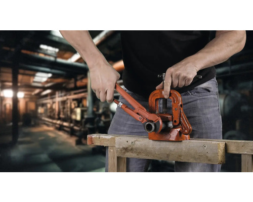 O persoană folosește o menghină pentru țevi și o cheie reglabilă pe o suprafață de lemn.