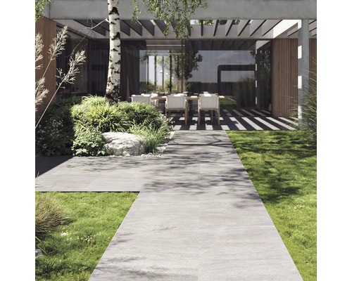 Scenă de grădină cu pavaj, gazon și zonă de relaxare în fundal