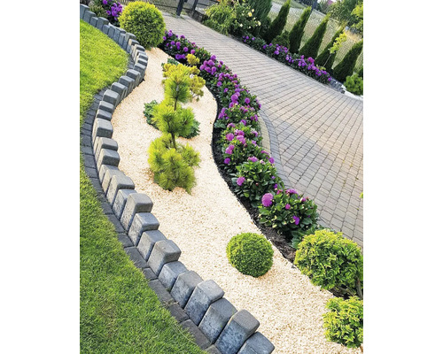 Alei amenajată în grădină cu pietriș, plante și borduri de gazon