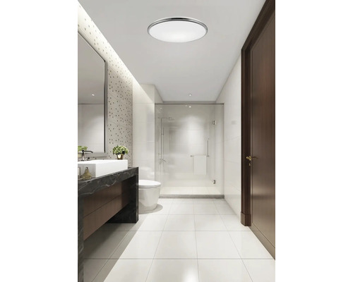 Baie modernă cu chiuvetă, toaletă și duș sub o lampă rotundă de plafon