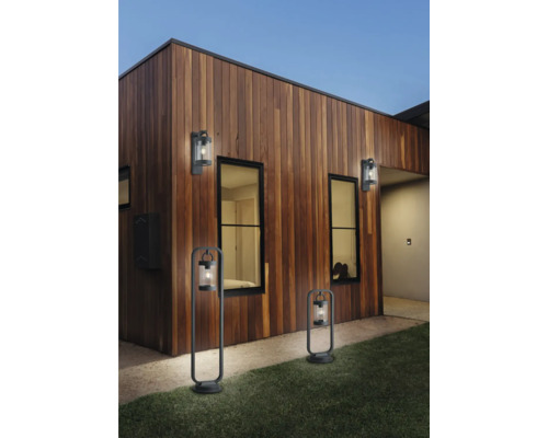 Exteriorul unei case cu perete de lemn și lămpi de exterior aprinse