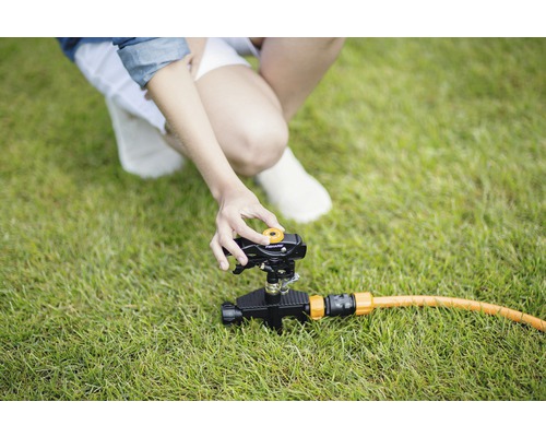 Persoană care reglează aspersorul de gazon pe gazon