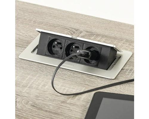 Bloc de prize retractabil cu trei prize și o fișă conectată pe o suprafață din lemn