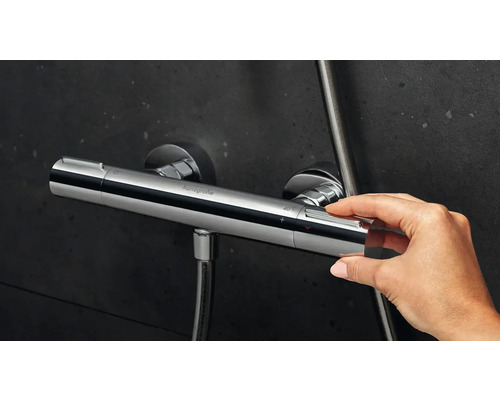 Prim-plan cu o mână care operează un termostat de duș Hansgrohe